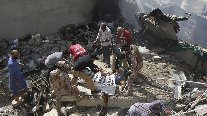 A firefighter tries to put out fire caused by plane crash in Karachi, Pakistan, Friday, May 22, 2020. An aviation official says a passenger plane belonging to state-run Pakistan International Airlines carrying more than 100 passengers and crew has crashed near the southern port city of Karachi. There were no immediate reports on the number of casualties. (AP Photo/Fareed Khan)