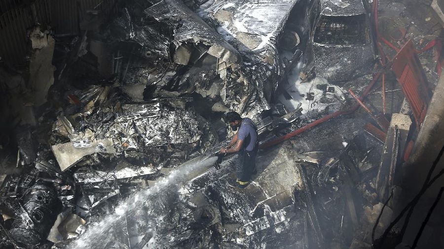 A firefighter tries to put out fire caused by plane crash in Karachi, Pakistan, Friday, May 22, 2020. An aviation official says a passenger plane belonging to state-run Pakistan International Airlines carrying more than 100 passengers and crew has crashed near the southern port city of Karachi. There were no immediate reports on the number of casualties. (AP Photo/Fareed Khan)