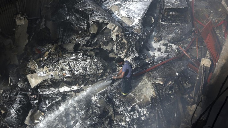 A firefighter tries to put out fire caused by plane crash in Karachi, Pakistan, Friday, May 22, 2020. An aviation official says a passenger plane belonging to state-run Pakistan International Airlines carrying more than 100 passengers and crew has crashed near the southern port city of Karachi. There were no immediate reports on the number of casualties. (AP Photo/Fareed Khan)