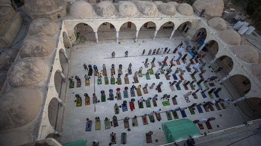 Worshippers wearing protective face masks offer Eid al-Fitr prayers outside a mosque to help prevent the spread of the coronavirus, in Tehran, Iran, Sunday, May 24, 2020. Muslims worldwide celebrate one of their biggest holidays under the long shadow of the coronavirus, with millions confined to their homes and others gripped by economic concerns during what is usually a festive time of shopping and celebration. In Iran, which has endured the deadliest outbreak in the Middle East, authorities have imposed few restrictions ahead of the holiday aside from cancelling mass prayers in Tehran traditionally led by Supreme Leader Ayatollah Ali Khamenei. (AP Photo/Vahid Salemi)