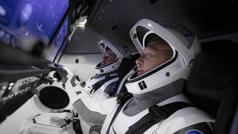 This Thursday, March 19, 2020 photo made available by SpaceX shows NASA astronauts Bob Behnken and Doug Hurley during flight simulator testing at the Kennedy Space Center in Cape Canaveral, Fla., with SpaceX teams in Firing Room 4 at NASA's Kennedy Space Center, SpaceX's Mission Control in Hawthorne, Calif., and NASA flight controllers in Mission Control Houston, for a full simulation of launch and docking of the Crew Dragon spacecraft. (SpaceX via AP)