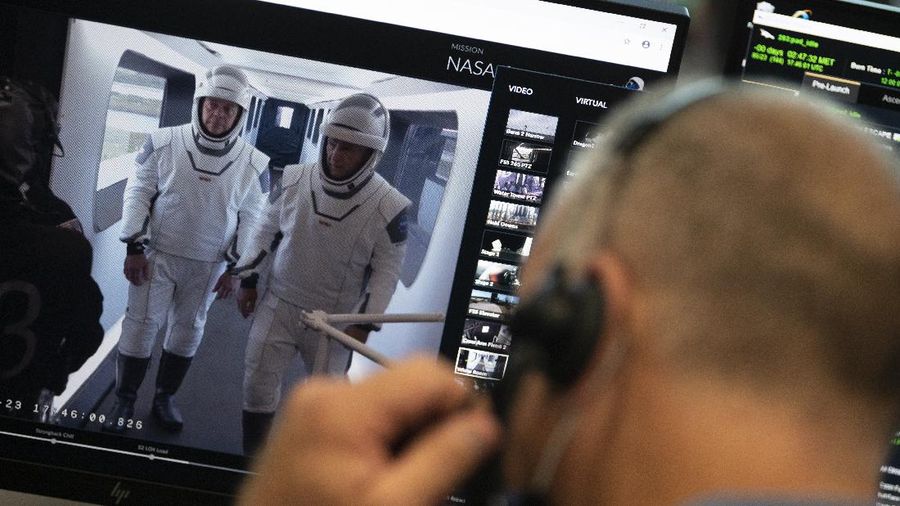 This Thursday, March 19, 2020 photo made available by SpaceX shows NASA astronauts Bob Behnken and Doug Hurley during flight simulator testing at the Kennedy Space Center in Cape Canaveral, Fla., with SpaceX teams in Firing Room 4 at NASA's Kennedy Space Center, SpaceX's Mission Control in Hawthorne, Calif., and NASA flight controllers in Mission Control Houston, for a full simulation of launch and docking of the Crew Dragon spacecraft. (SpaceX via AP)