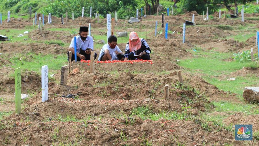 Taman Pemakaman Umum (TPU) Tegal Alur, Kalideres, Jakarta Barat, ramai oleh peziarah pada Hari Raya Idul Fitri 1441 Hijriyah, Ahad (26/5/20). Sejak pagi, keberadaan peziarah pada hari Lebaran ketiga tampak merata di blok pemakaman umum maupun blok makam khusus pasien Covid-19.
Terdapat pembatas garis polisi yang membedakan blok makam umum dan makam pasien Covid-19. TPU Tegal Alur diketahui merupakan salah satu makam yang khusus diperuntukkan jenazah pasien positif Covid-19.
Protokol kesehatan covid-19 diberlakukan secara ketat di kawasan TPU Tegal Alur. Peziarah wajib menggunakan masker dan mencuci tangan dengan sabun serta air mengalir. Selain itu, sebelum peziarah masuk dan keluar TPU Tegal Alur, terutama di blok makam pasien Covid-19, petugas melakukan disinfeksi kepada mereka.
Terik siang menyengat tak menghalangi niat peziarah berdoa di pusara keluarga yang telah wafat, seperti salah seorang pengunjung makam, Teguh (30). Bersama beberapa anggota keluarganya, Teguh berziarah ke makam ayahnya yang dimakamkan dengan protokol Covid-19 di TPU Tegal Alur.