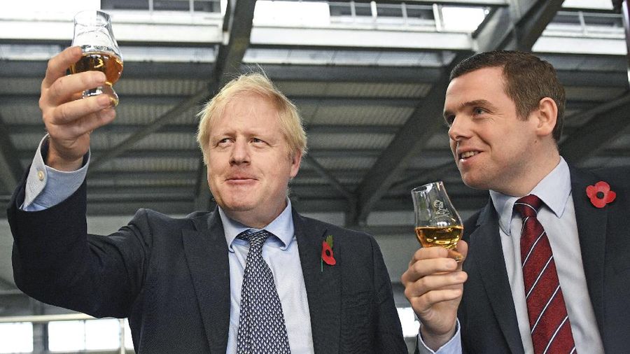 FILE - In this file photo dated Nov. 7, 2019, showing Britain's Prime Minister Boris Johnson alongside Douglas Ross, parliamentary under-secretary of state for Scotland, right in Moray, Scotland.   Junior British government minister Douglas Ross has quit Tuesday May 26, 2020, over Prime Minister Boris Johnson’s failure to fire his top aide Dominic Cummings for allegedly breaching COVID-19 coronavirus lockdown rules. (Stefan Rousseau / PA via AP)