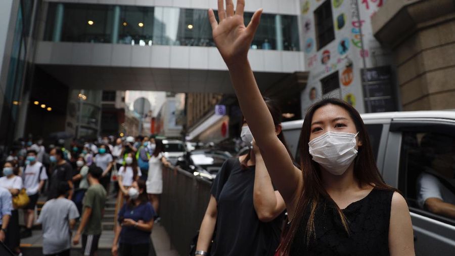 Riot police standing guard as a woman tries to cross the street in the Central district of Hong Kong, Wednesday, May 27, 2020. Hong Kong police massed outside the legislature complex Wednesday, ahead of debate on a bill that would criminalize abuse of the Chinese national anthem in the semi-autonomous city. (AP Photo/Vincent Yu)