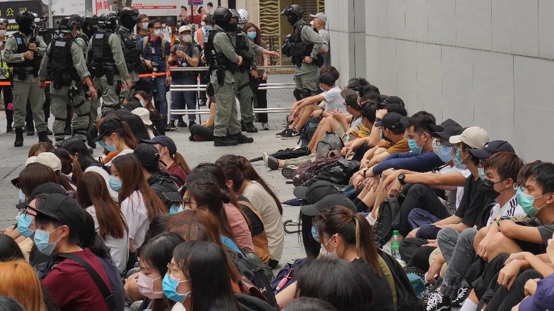 Riot police standing guard as a woman tries to cross the street in the Central district of Hong Kong, Wednesday, May 27, 2020. Hong Kong police massed outside the legislature complex Wednesday, ahead of debate on a bill that would criminalize abuse of the Chinese national anthem in the semi-autonomous city. (AP Photo/Vincent Yu)