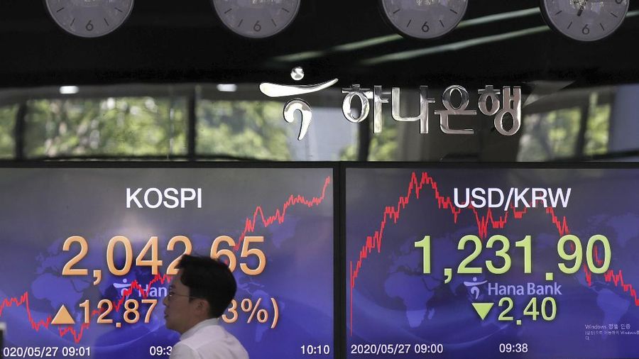 A currency trader talks near the screens showing the Korea Composite Stock Price Index (KOSPI), right, and the foreign exchange rates at the foreign exchange dealing room in Seoul, South Korea, Wednesday, May 27, 2020. Major Asian stock markets have declined as US-Chinese tension over Hong Kong competes with optimism about recovery from the coronavirus pandemic. (AP Photo/Lee Jin-man)