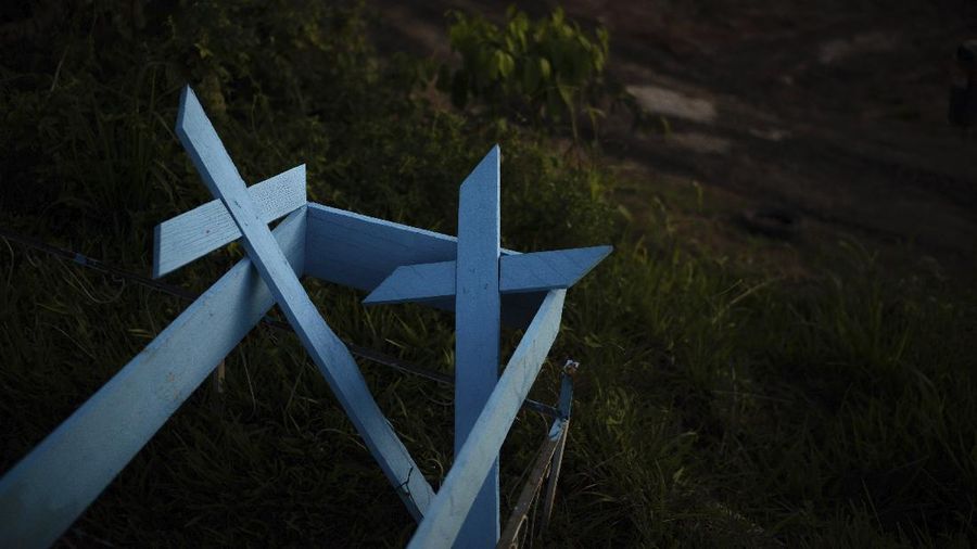 Painted wooden crosses lay on the roadside of a new section of the Nossa Senhora Aparecida cemetery in Manaus, Brazil, Saturday, May 16, 2020. The new section was opened last month to cope with a sudden surge in deaths in the city, but most were not tested for COVID-19. (AP Photo/Felipe Dana)