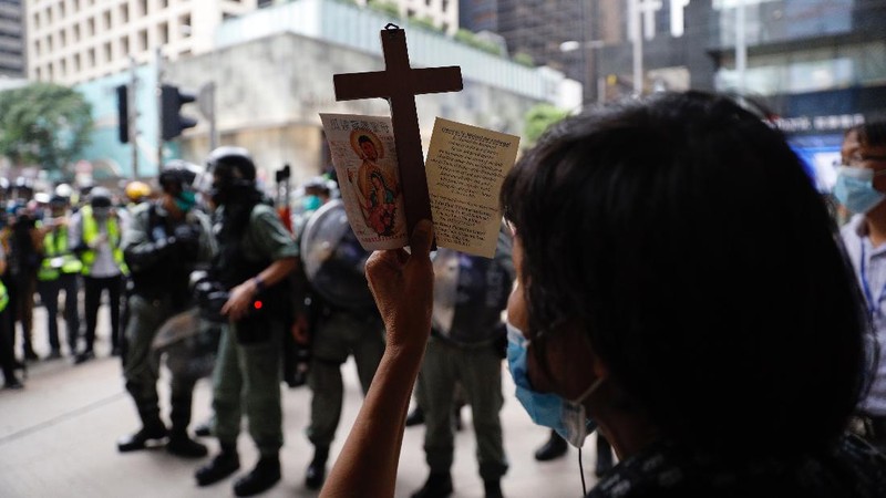Riot police standing guard as a woman tries to cross the street in the Central district of Hong Kong, Wednesday, May 27, 2020. Hong Kong police massed outside the legislature complex Wednesday, ahead of debate on a bill that would criminalize abuse of the Chinese national anthem in the semi-autonomous city. (AP Photo/Vincent Yu)