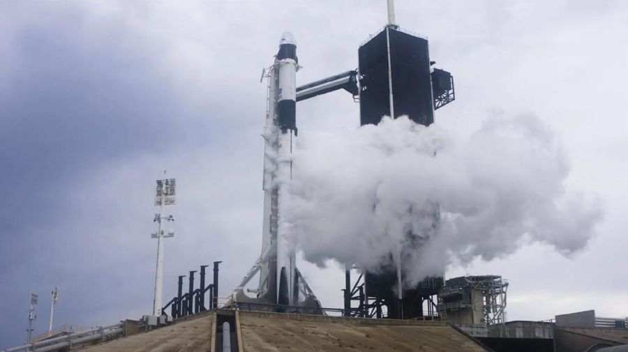 In this Wednesday, May 27, 2020 image from video made available by SpaceX, NASA astronauts  Doug Hurley, center, and Bob Behnken, left, confer with technicians after leaving the Crew Dragon capsule at the Kennedy Space Center in Cape Canaveral, Fla., after an aborted launch due to weather problems. (SpaceX via AP)