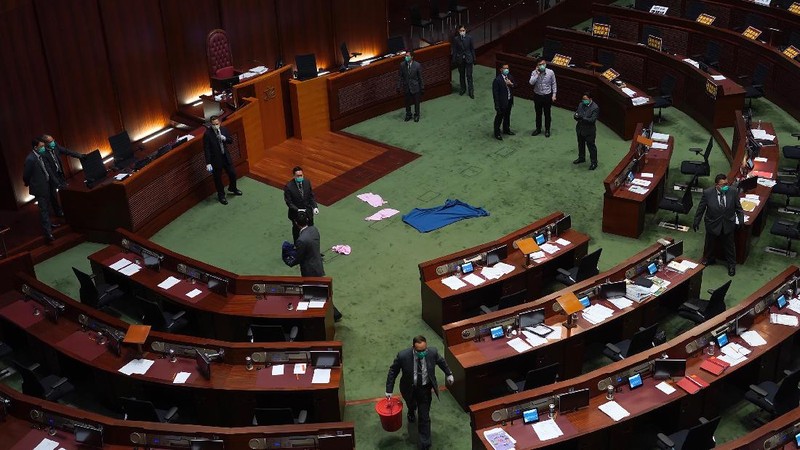 Staff from the Legislative Council cover the floor with towels after a pro-democracy lawmaker hurled an object during the second day of debate on a bill that would criminalize insulting or abusing the Chinese anthem in Hong Kong, Thursday, May 28, 2020. The lawmaker ejected later had spilled a substance on the floor that had to be cleaned up by firefighters wearing protective gear.(AP Photo/Vincent Yu)