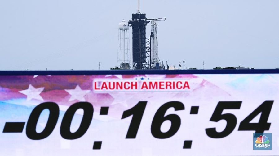 In this Wednesday, May 27, 2020 image from video made available by SpaceX, NASA astronauts  Doug Hurley, center, and Bob Behnken, left, confer with technicians after leaving the Crew Dragon capsule at the Kennedy Space Center in Cape Canaveral, Fla., after an aborted launch due to weather problems. (SpaceX via AP)