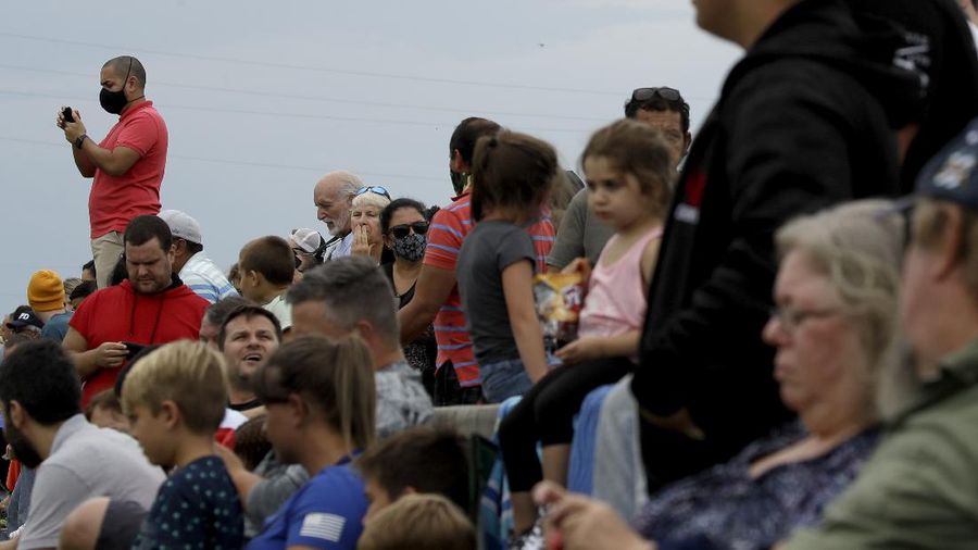 In this Wednesday, May 27, 2020 image from video made available by SpaceX, NASA astronauts  Doug Hurley, center, and Bob Behnken, left, confer with technicians after leaving the Crew Dragon capsule at the Kennedy Space Center in Cape Canaveral, Fla., after an aborted launch due to weather problems. (SpaceX via AP)