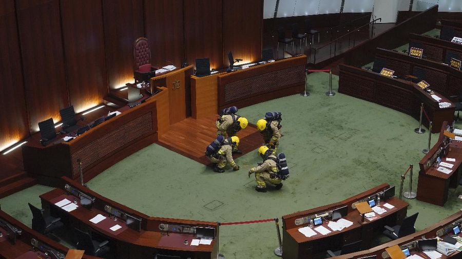 Staff from the Legislative Council cover the floor with towels after a pro-democracy lawmaker hurled an object during the second day of debate on a bill that would criminalize insulting or abusing the Chinese anthem in Hong Kong, Thursday, May 28, 2020. The lawmaker ejected later had spilled a substance on the floor that had to be cleaned up by firefighters wearing protective gear.(AP Photo/Vincent Yu)