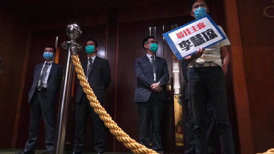 Staff from the Legislative Council cover the floor with towels after a pro-democracy lawmaker hurled an object during the second day of debate on a bill that would criminalize insulting or abusing the Chinese anthem in Hong Kong, Thursday, May 28, 2020. The lawmaker ejected later had spilled a substance on the floor that had to be cleaned up by firefighters wearing protective gear.(AP Photo/Vincent Yu)