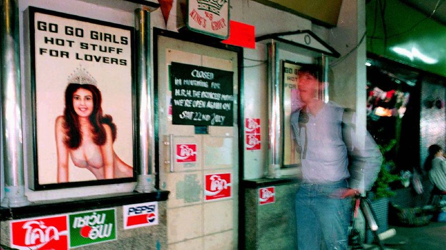 A lone tourist walks past a closed go-go bar on Patpong Road in the midst of Bangkok's red light district late Thursday night July 20, 1995. In mourning for Thailand's Princess Mother, who passed away on July 18, 1995, all entertainment establishments have closed for 3 days. (AP Photo/Charles Dharapak)