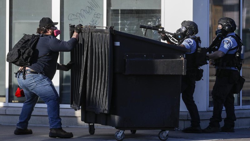 A protester gestures in front of the burning 3rd Precinct building of the Minneapolis Police Department on Thursday, May 28, 2020, in Minneapolis. Protests over the death of George Floyd, a black man who died in police custody Monday, broke out in Minneapolis for a third straight night. (AP Photo/Julio Cortez)