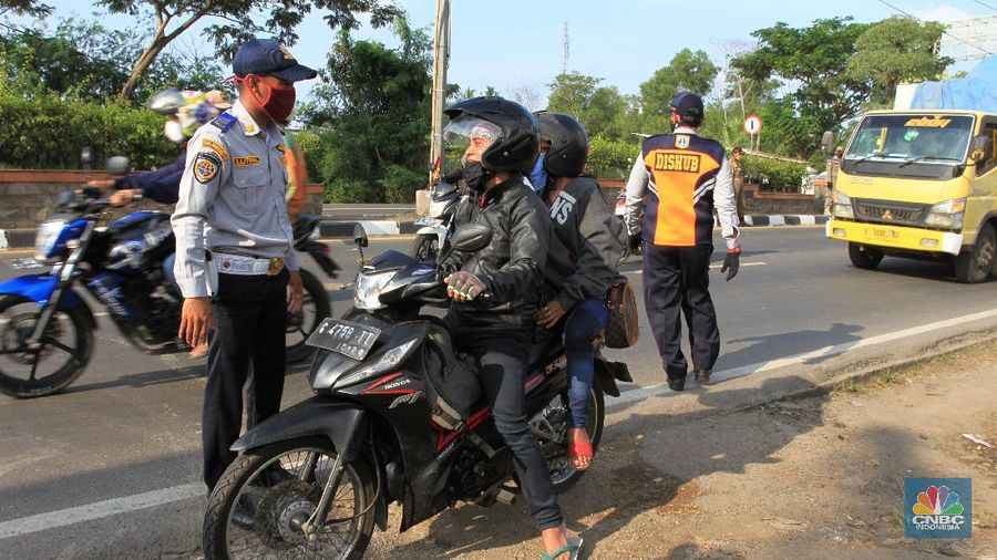 Petugas Dinas Perhubungan (Dishub) akan melakukan pemeriksaan terhadap pengguna kendaraan yang akan memasuki wilayah DKI Jakarta di wilayah perbatasan Bekasi-Karawang, Jawa Barat, Jumat (29/5/2020). Berdasarkan data Dishub Provinsi DKI Jakarta per Rabu (27/5) malam, sebanyak 6.364 kendaraan telah dikembalikan karena mencoba memasuki wilayah Jakarta tanpa memiliki Surat Izin Masuk-Masuk (SIKM) di masa arus balik Lebaran 2020. CNBC Indonesia/Tri Susilo
Tim Gugus Tugas Percepatan Penanganan Covid-19 Kabupaten Karawang, Jabar, menyatakan, terdapat delapan check point atau penyekatan kendaraan pemudik di wilayah Karawang.
Delapan titik check point itu di antaranya di Jembatan Tanjungpura, Jembatan Sian Djin Kupoh, Kobak Biru, Cibeet, Jembatan Rengasdengklok-Bekasi, Jembatan Batujaya-Bekasi, dan ada dua pos di Karawang Kota.
Pencegahan pergerakan pemudik itu berkaitan dengan upaya pemerintah yang melarang mudik pada Lebaran tahun ini sebagai bagian dari mencegah penyebaran virus corona.
Pantauan CNBC Indonesia dilapangan masih banyak pengendara yang masih melanggar peraturan yang sudah ditetapkan oleh pemerintah, contoh surat Surat Izin Keluar Masuk (SIKM).
Warga yang kedapatan tidak memiliki surat (SIKM) akan diputar balik.
Salah satu warga yang mudik dari Tegal, Jawa Tengah menggunakan sepeda motor diberhentikan oleh petugas pengaman perihal SIKM yang tidak ia miliki, tetapi dirinya mempunyai surat jalan untuk pulang ke Jakarta dari pihak kepolisian di Jawa Tengah. (CNBC Indonesia/ Tri Susilo)