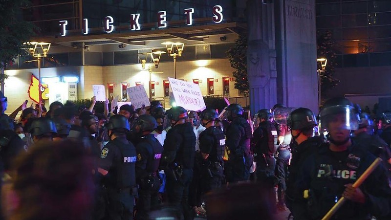 A protester gestures in front of the burning 3rd Precinct building of the Minneapolis Police Department on Thursday, May 28, 2020, in Minneapolis. Protests over the death of George Floyd, a black man who died in police custody Monday, broke out in Minneapolis for a third straight night. (AP Photo/Julio Cortez)