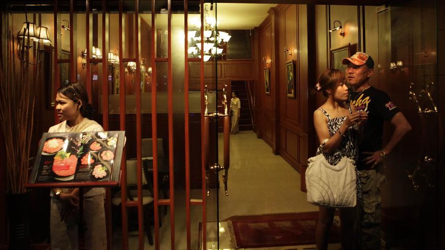 A Thai couple waits for taxi after dinner in the Patpong area, near to the anti-government protesters encampment, which re-opened after an interval of two weeks, with precautionary midnight to early morning curfew in downtown Bangkok, Thailand, Tuesday, May 25, 2010. (AP Photo/ Manish Swarup)