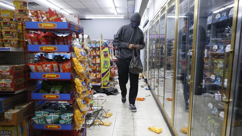 A protester breaks a window of a business during a protest over the death of George Floyd Friday, May 29, 2020, in Los Angeles. Protests have been erupting all over the country after George Floyd died earlier this week in police custody in Minneapolis. (AP Photo/Ringo H.W. Chiu)
