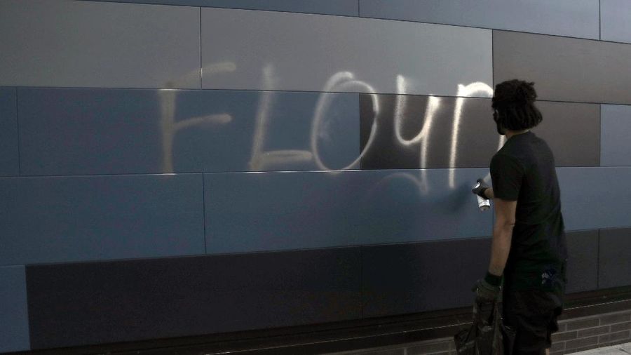 A protester spray paints George Floyd's name Friday, May 29, 2020, in Minneapolis. Protests continued following the death of Floyd, who died after being restrained by Minneapolis police officers on Memorial Day. (AP Photo/Julio Cortez)