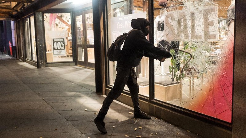 A protester breaks a window of a business during a protest over the death of George Floyd Friday, May 29, 2020, in Los Angeles. Protests have been erupting all over the country after George Floyd died earlier this week in police custody in Minneapolis. (AP Photo/Ringo H.W. Chiu)