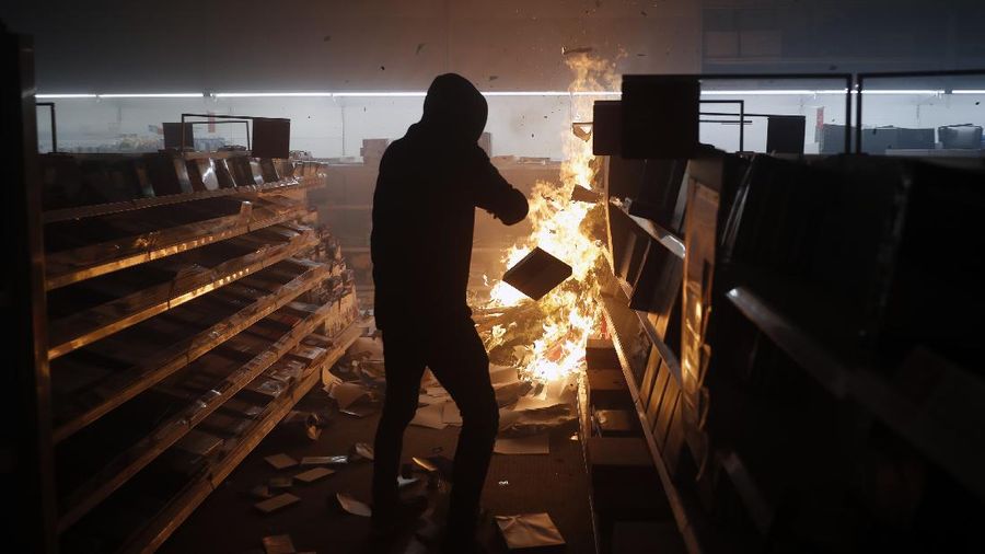 A protester breaks a window of a business during a protest over the death of George Floyd Friday, May 29, 2020, in Los Angeles. Protests have been erupting all over the country after George Floyd died earlier this week in police custody in Minneapolis. (AP Photo/Ringo H.W. Chiu)