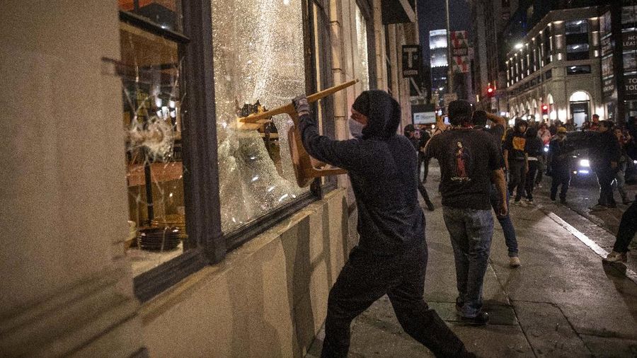 A protester breaks a window of a business during a protest over the death of George Floyd Friday, May 29, 2020, in Los Angeles. Protests have been erupting all over the country after George Floyd died earlier this week in police custody in Minneapolis. (AP Photo/Ringo H.W. Chiu)