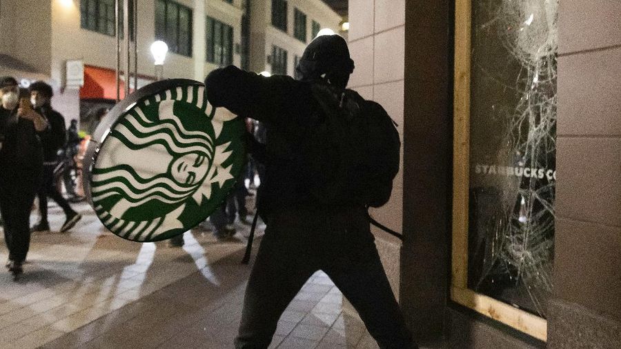 A protester breaks a window of a business during a protest over the death of George Floyd Friday, May 29, 2020, in Los Angeles. Protests have been erupting all over the country after George Floyd died earlier this week in police custody in Minneapolis. (AP Photo/Ringo H.W. Chiu)