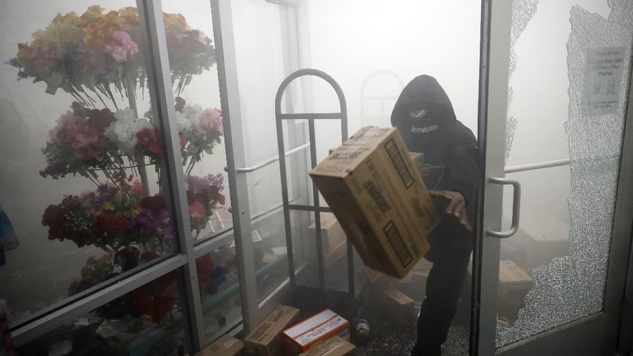 A protester breaks a window of a business during a protest over the death of George Floyd Friday, May 29, 2020, in Los Angeles. Protests have been erupting all over the country after George Floyd died earlier this week in police custody in Minneapolis. (AP Photo/Ringo H.W. Chiu)