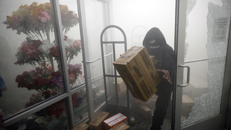 A protester breaks a window of a business during a protest over the death of George Floyd Friday, May 29, 2020, in Los Angeles. Protests have been erupting all over the country after George Floyd died earlier this week in police custody in Minneapolis. (AP Photo/Ringo H.W. Chiu)