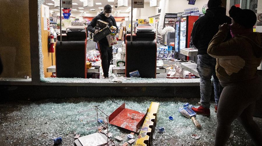 A woman carries merchandise from a Union Square Victoria's Secret store in San Francisco on Saturday, May 30, 2020. Widespread vandalizing occurred at stores throughout San Francisco following the death of George Floyd, a handcuffed black man in police custody in Minneapolis. (AP Photo/Noah Berger)