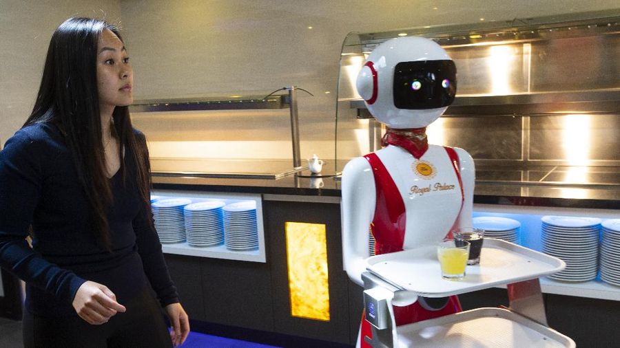 Owners Shu Lei Hu, left, and her husband Shao Song Hu, right, demonstrate the use of robots for serving purposes or for dirty dishes collection, as part of a tryout of measures to respect social distancing and help curb the spread of the COVID-19 coronavirus, at the family's Royal Palace restaurant in Renesse, south-western Netherlands, Wednesday, May 27, 2020. (AP Photo/Peter Dejong)