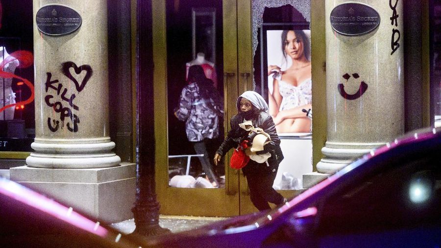 A woman carries merchandise from a Union Square Victoria's Secret store in San Francisco on Saturday, May 30, 2020. Widespread vandalizing occurred at stores throughout San Francisco following the death of George Floyd, a handcuffed black man in police custody in Minneapolis. (AP Photo/Noah Berger)