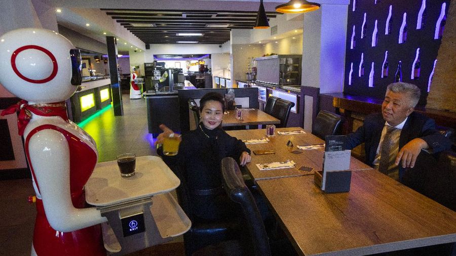 Owners Shu Lei Hu, left, and her husband Shao Song Hu, right, demonstrate the use of robots for serving purposes or for dirty dishes collection, as part of a tryout of measures to respect social distancing and help curb the spread of the COVID-19 coronavirus, at the family's Royal Palace restaurant in Renesse, south-western Netherlands, Wednesday, May 27, 2020. (AP Photo/Peter Dejong)