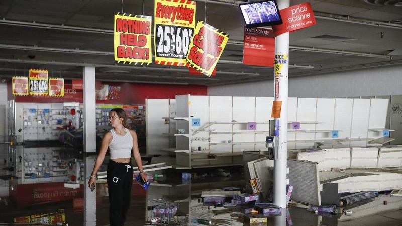 A woman carries merchandise from a Union Square Victoria's Secret store in San Francisco on Saturday, May 30, 2020. Widespread vandalizing occurred at stores throughout San Francisco following the death of George Floyd, a handcuffed black man in police custody in Minneapolis. (AP Photo/Noah Berger)