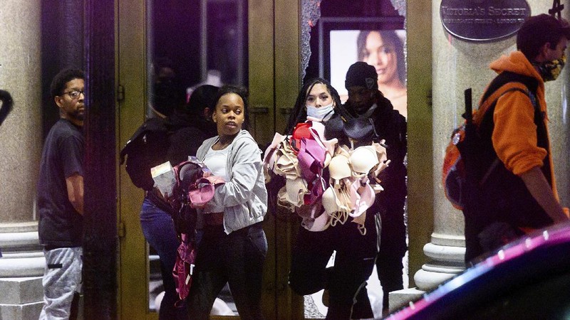A woman carries merchandise from a Union Square Victoria's Secret store in San Francisco on Saturday, May 30, 2020. Widespread vandalizing occurred at stores throughout San Francisco following the death of George Floyd, a handcuffed black man in police custody in Minneapolis. (AP Photo/Noah Berger)
