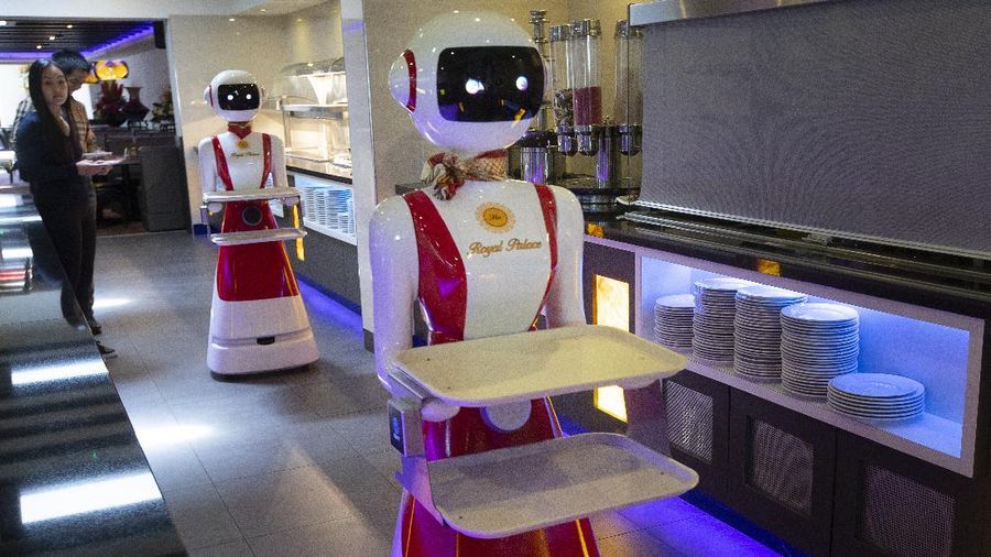 Owners Shu Lei Hu, left, and her husband Shao Song Hu, right, demonstrate the use of robots for serving purposes or for dirty dishes collection, as part of a tryout of measures to respect social distancing and help curb the spread of the COVID-19 coronavirus, at the family's Royal Palace restaurant in Renesse, south-western Netherlands, Wednesday, May 27, 2020. (AP Photo/Peter Dejong)