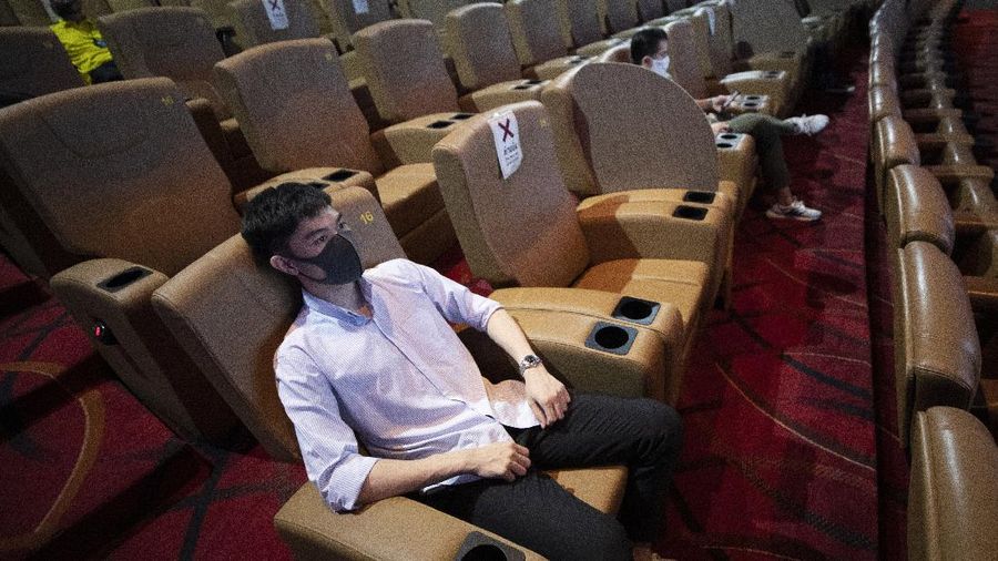 a movie goer wears a face mask to help curb the spread of the coronavirus as he buys ticket at the Paragon Cineplex movie theater in Bangkok, Thailand, Monday, June 1, 2020. Thai authorities allowed movie theater and other businesses to reopen, selectively easing restrictions against the coronavirus. (AP Photo/Sakchai Lalit)