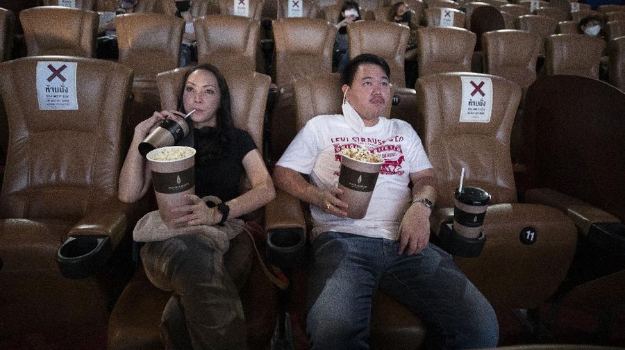 a movie goer wears a face mask to help curb the spread of the coronavirus as he buys ticket at the Paragon Cineplex movie theater in Bangkok, Thailand, Monday, June 1, 2020. Thai authorities allowed movie theater and other businesses to reopen, selectively easing restrictions against the coronavirus. (AP Photo/Sakchai Lalit)