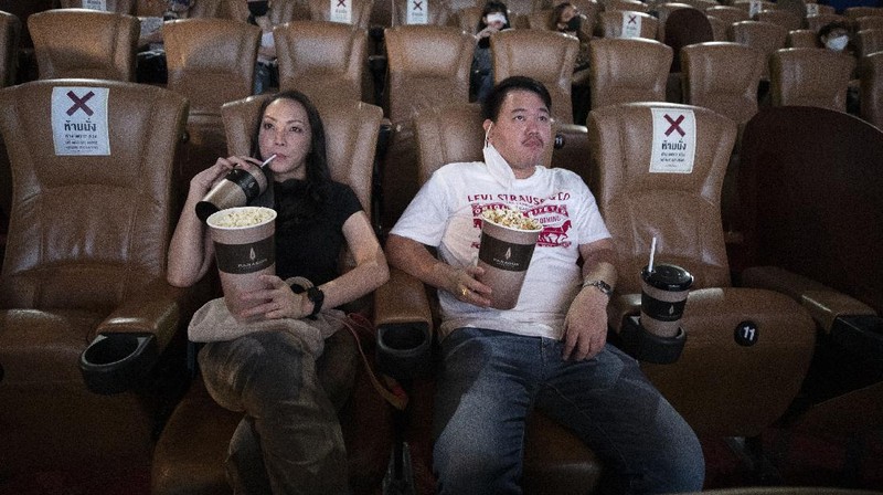 a movie goer wears a face mask to help curb the spread of the coronavirus as he buys ticket at the Paragon Cineplex movie theater in Bangkok, Thailand, Monday, June 1, 2020. Thai authorities allowed movie theater and other businesses to reopen, selectively easing restrictions against the coronavirus. (AP Photo/Sakchai Lalit)