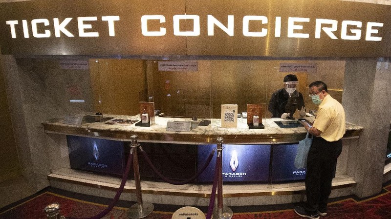 a movie goer wears a face mask to help curb the spread of the coronavirus as he buys ticket at the Paragon Cineplex movie theater in Bangkok, Thailand, Monday, June 1, 2020. Thai authorities allowed movie theater and other businesses to reopen, selectively easing restrictions against the coronavirus. (AP Photo/Sakchai Lalit)