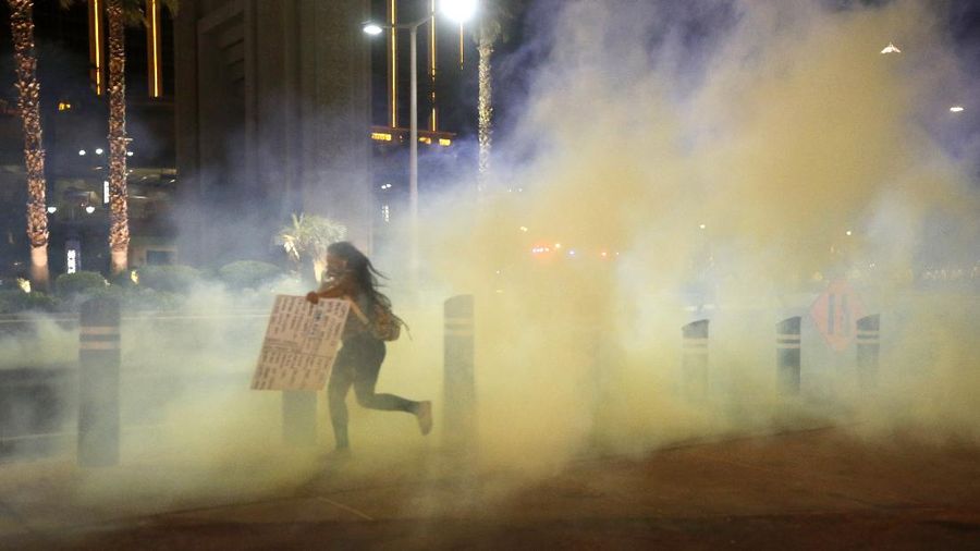 A protester runs through tear gas on the Las Vegas Strip on Sunday, May 31, 2020, in Las Vegas, during demonstrations over the death of George Floyd, who died May 25 after he was pinned at the neck by a Minneapolis police officer. (AP Photo/Steve Marcus)