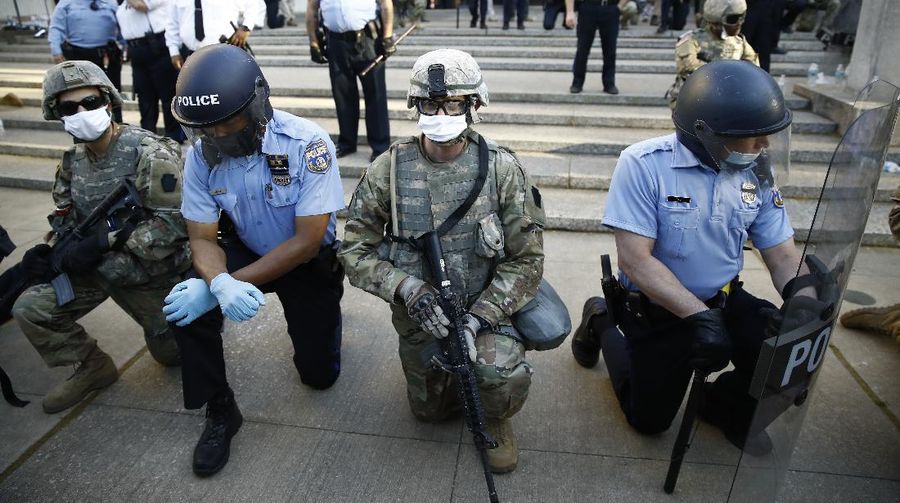A police officer kneels with a demonstrator in solidarity in front of the Lewiston police station Monday, June 1, 2020, at the conclusion of a rally in reaction to the death of George Floyd, who died May 25 in Minneapolis after being restrained by police. (Andree Kehn/Sun Journal via AP)