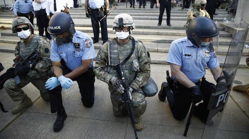 A police officer kneels with a demonstrator in solidarity in front of the Lewiston police station Monday, June 1, 2020, at the conclusion of a rally in reaction to the death of George Floyd, who died May 25 in Minneapolis after being restrained by police. (Andree Kehn/Sun Journal via AP)