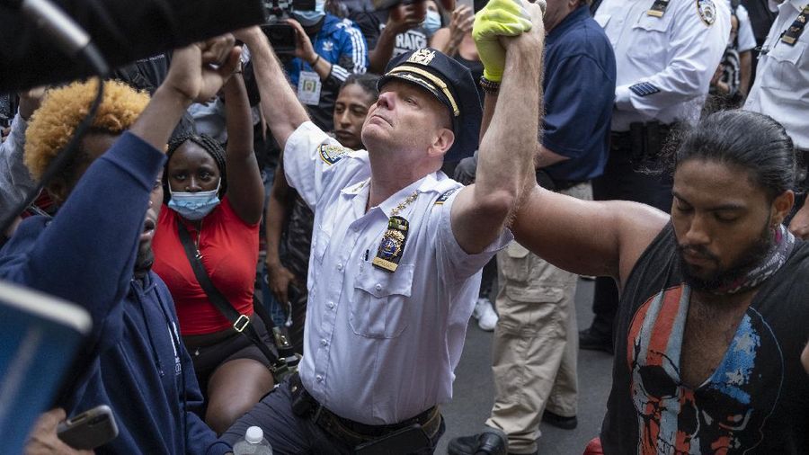 A police officer kneels with a demonstrator in solidarity in front of the Lewiston police station Monday, June 1, 2020, at the conclusion of a rally in reaction to the death of George Floyd, who died May 25 in Minneapolis after being restrained by police. (Andree Kehn/Sun Journal via AP)