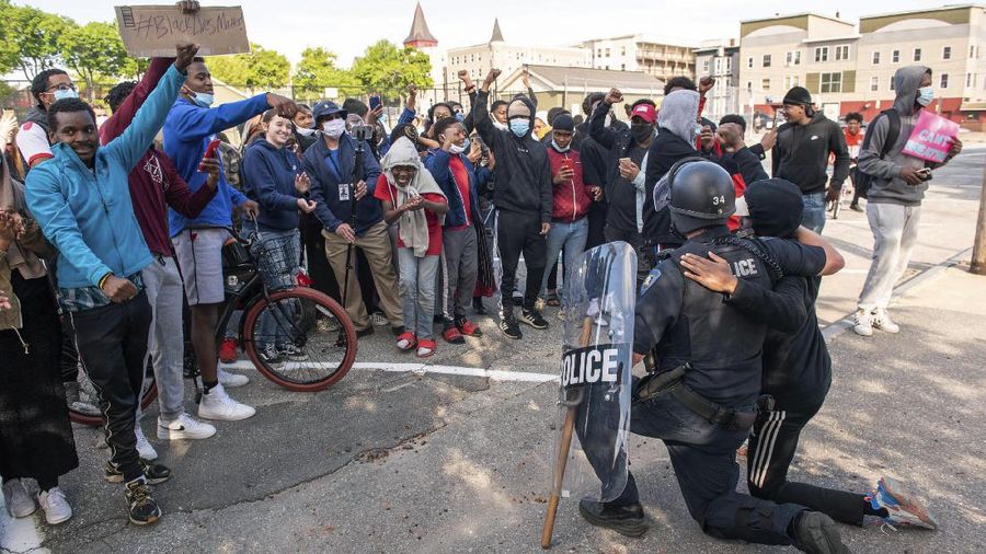 A police officer kneels with a demonstrator in solidarity in front of the Lewiston police station Monday, June 1, 2020, at the conclusion of a rally in reaction to the death of George Floyd, who died May 25 in Minneapolis after being restrained by police. (Andree Kehn/Sun Journal via AP)