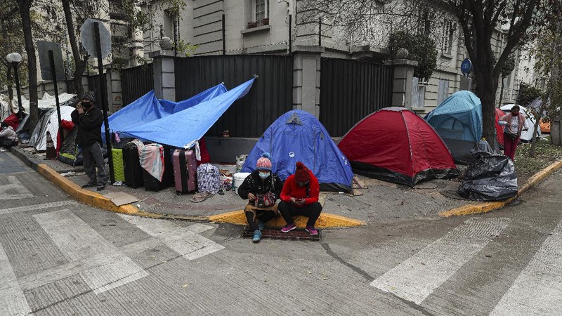 Para pekerja migran asal Peru membangun tenda di luar gedung konsulat Peru untuk menuntut repatriasi di tengah pandemi COVID-19 di Santiago, Chili. AP/Esteban Felix