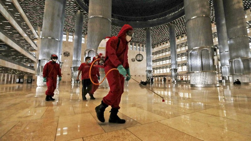 Seorang petugas pemadam kebakaran menyemprotkan desinfektan dalam upaya membantu mengekang penyebaran virus corona baru di Masjid Istiqlal di Jakarta. AP/Achmad Ibrahim